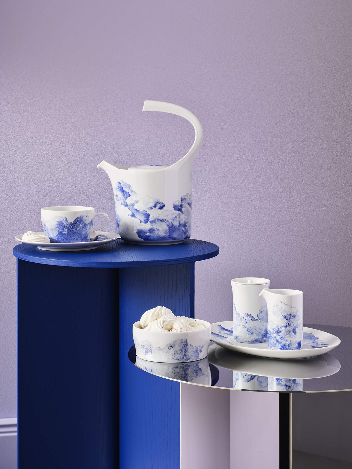 Porzellanservice mit wolkenartigem Design steht auf blauen und spiegelnden Tischen. Fürstenberg Porzellan.