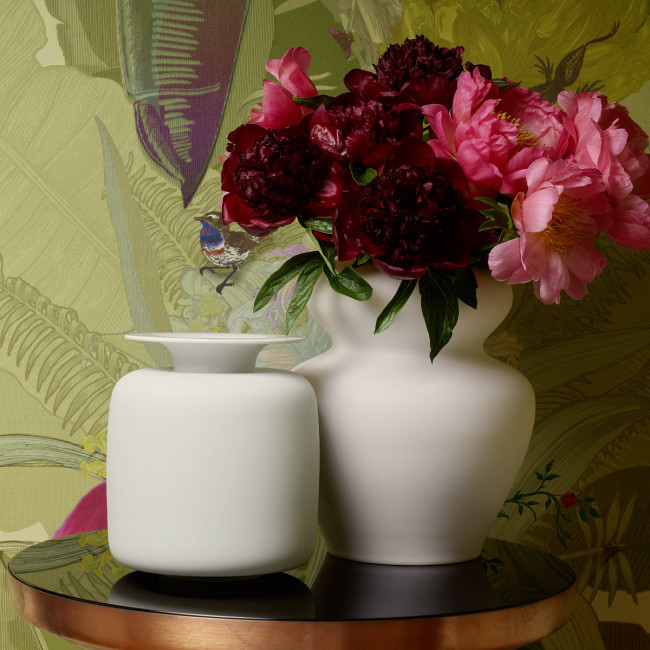 Weiße Vase mit bunten Blumen auf Tisch, vor gemustertem Hintergrund. Fürstenberg Porzellan.