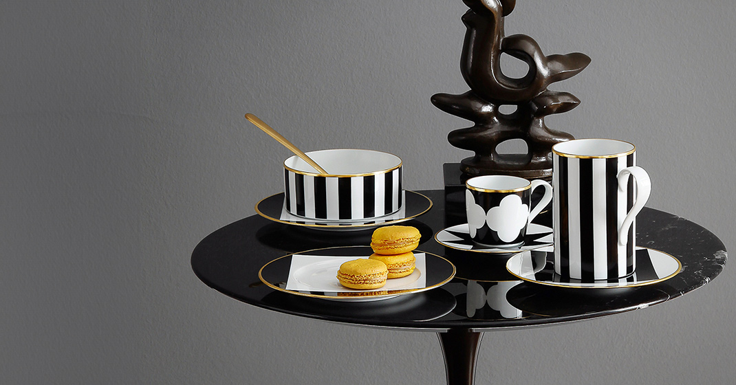 Schwarz-weiß gestreiftes Geschirr auf rundem Tisch mit goldenen Details, gelbe Macarons. Fürstenberg Porzellan.