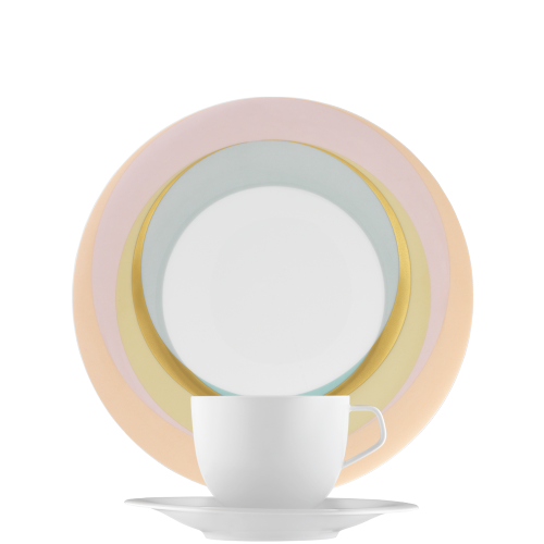 Weiße Tasse vor gestapelten, farbigen Tellern in Blau, Gelb, Rosa. Fürstenberg Porzellan. Weiße Tasse vor gestapelten, farbigen Tellern in Blau, Gelb, Rosa. Fürstenberg Porzellan.