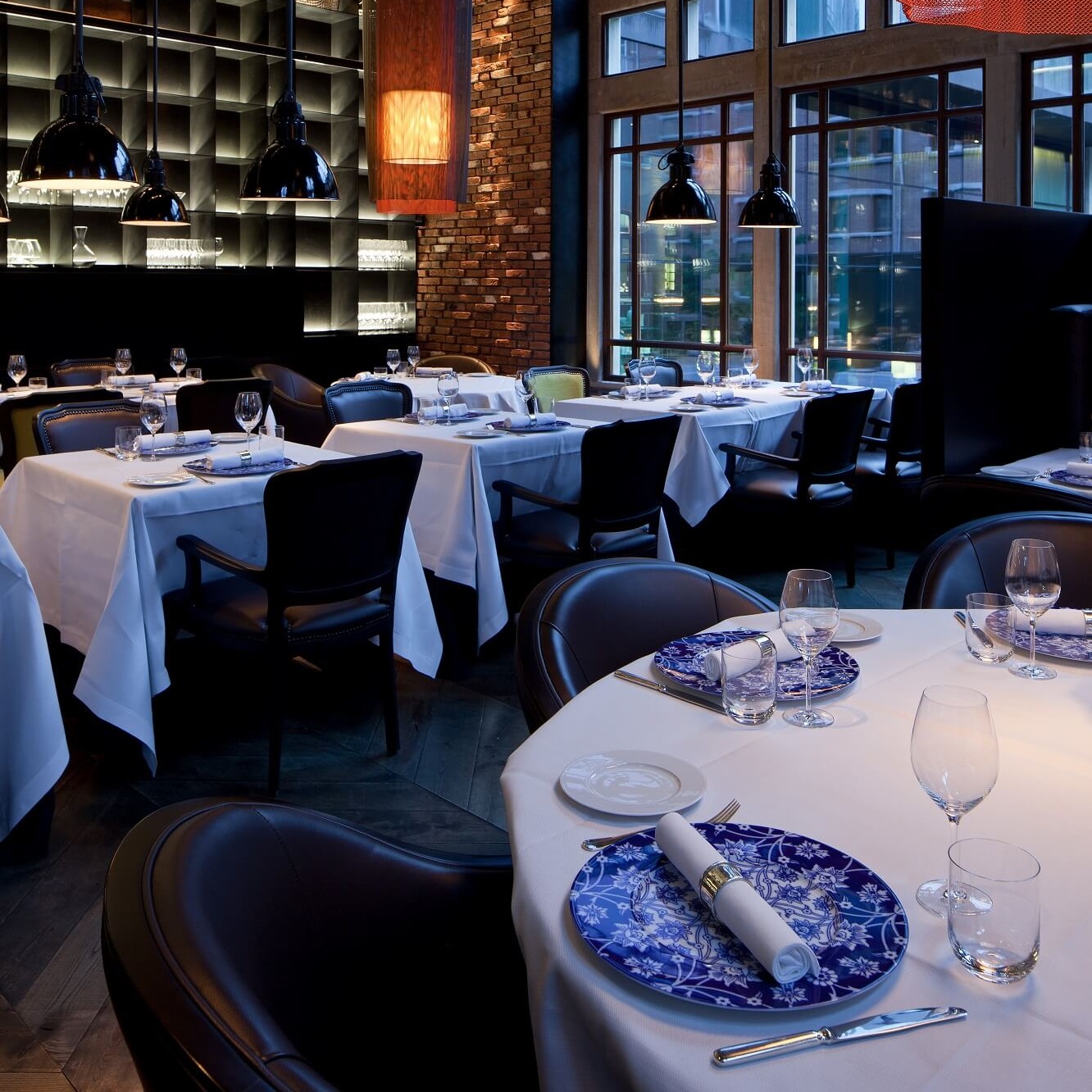 Restauranttische sind für Gäste gedeckt, mit blauen dekorativen Tellern. Fürstenberg Porzellan.