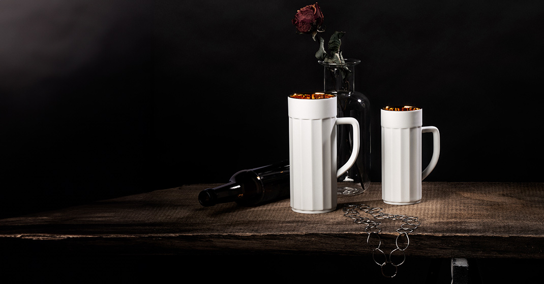 Zwei weiße Tassen auf Tisch neben Rosen in Vase und leere Flasche. Fürstenberg Porzellan.