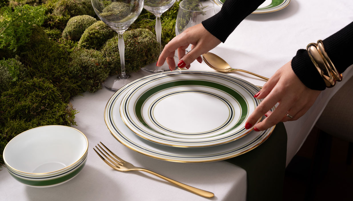 Eine Weihnachtstafel mit grünem Geschirr wird eingedeckt