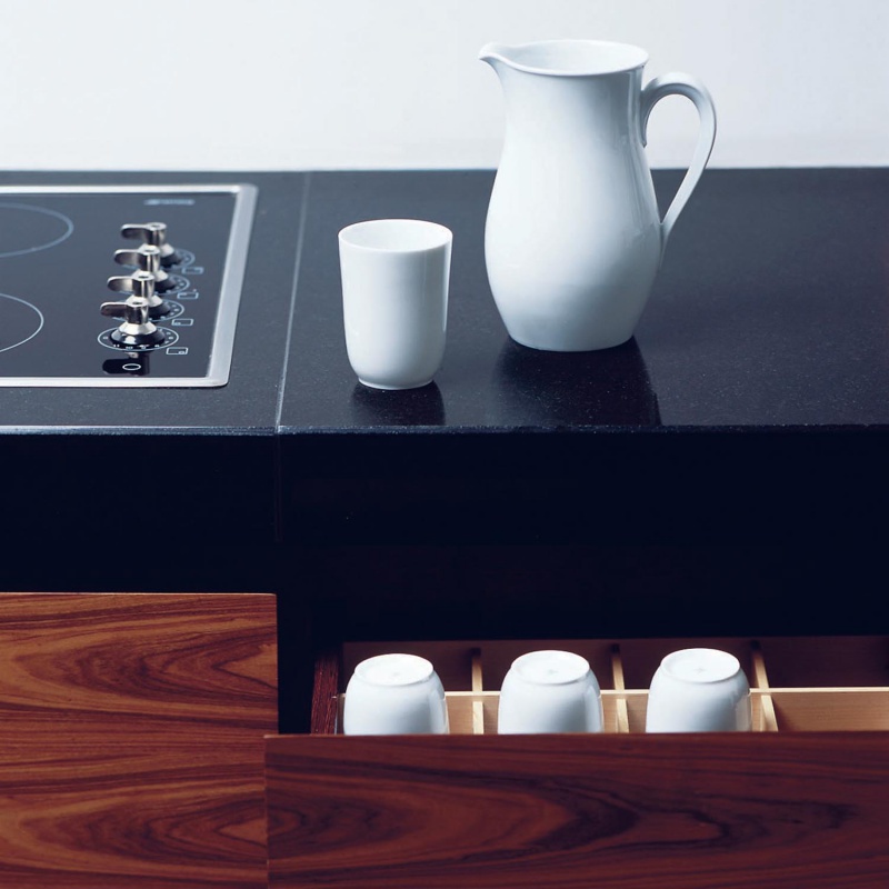 img2_ob_63910weiss_becher Weiße Porzellan-Kanne steht neben Tasse auf schwarzer Küchenarbeitsplatte. Fürstenberg Porzellan.