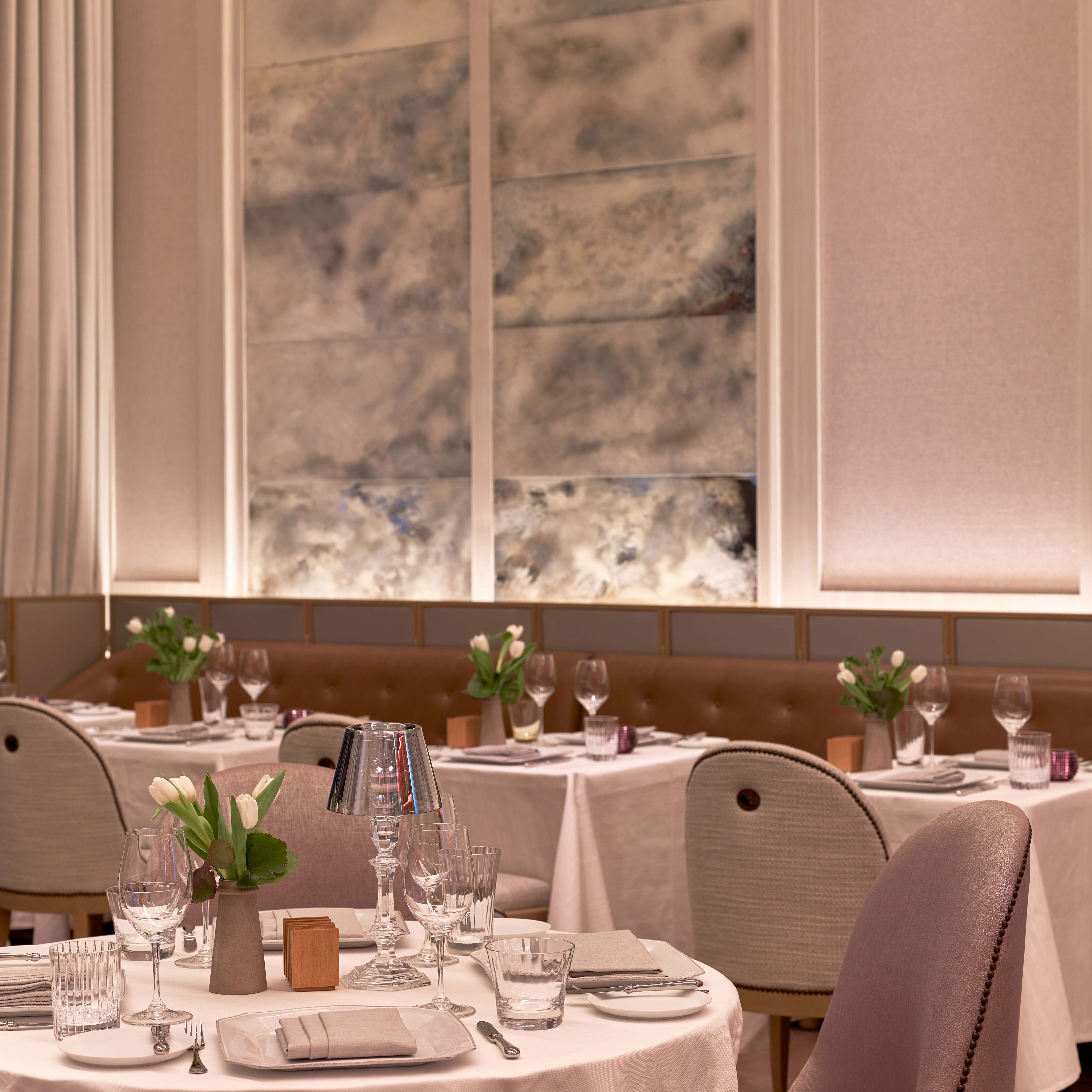 Elegant gedeckter Restauranttisch mit Blumen, Gläsern und Geschirr in modernem Ambiente. Fürstenberg Porzellan.