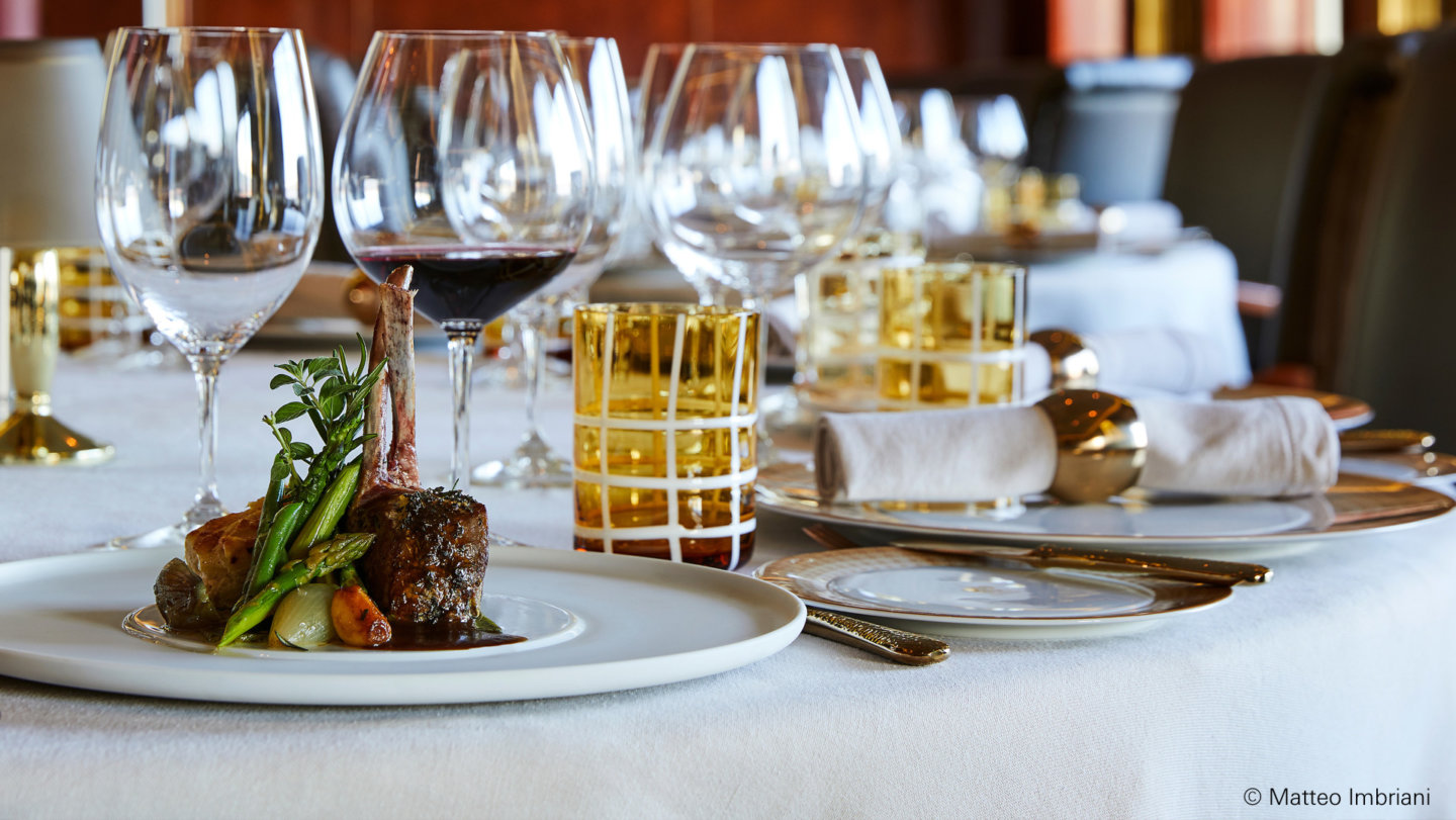 Elegantes Gedeck mit Fleischgericht, Weingläsern und dekorativen Servietten auf Tisch. Fürstenberg Porzellan.
